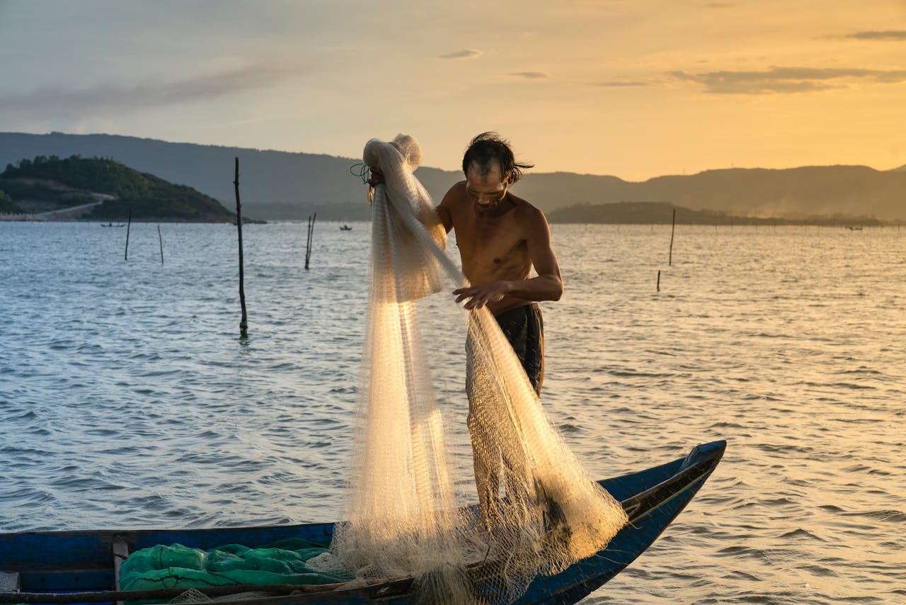 A fisherman casting a net at sunrise on a serene lake, capturing the tranquil beauty of the scene.